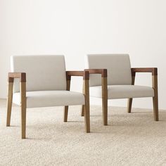 two chairs sitting next to each other on top of a carpeted floor in front of a white wall