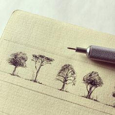 a pen sitting on top of a piece of paper with trees drawn on it,