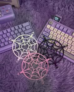 a pair of glasses sitting next to a computer keyboard on a purple rug with spider web