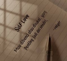 a pen sitting on top of a piece of paper next to a window with the words self love written on it