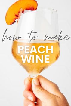 a person holding up a wine glass with an orange slice on the top and how to make peach wine in it