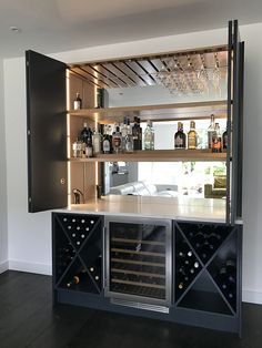 a bar with wine bottles and glasses on it in front of a wall mounted cabinet