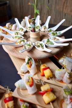 a wooden tray topped with lots of different types of sushi on top of serving utensils