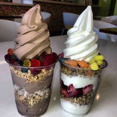 two desserts are sitting on a table with ice cream, fruit and granola