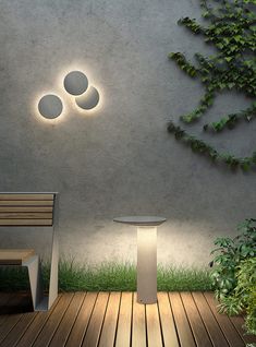 a table and chair on a wooden floor next to a wall with two circular lights