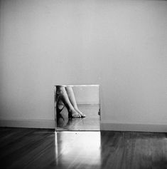 a black and white photo of a person's legs in a glass block on the floor