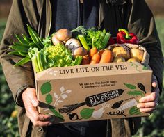 a man holding a box full of vegetables