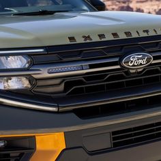 the front end of a green and black truck with an emblem on it's grille