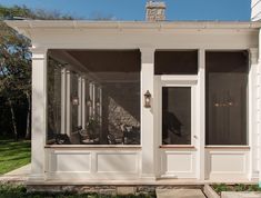 a screened porch with two chairs on the front and one sitting in the back yard