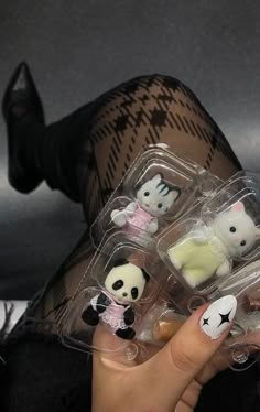 a woman with her legs crossed holding four small plastic animal figurines in their hands