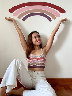 a woman sitting on the floor with her arms in the air