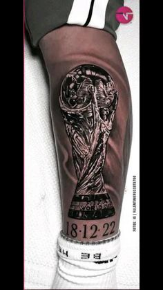 a person with a tattoo on their leg and the world cup in his hand is shown