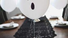 white balloons with faces on them are hanging from a table