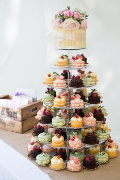 a tiered cake and cupcake display on a table