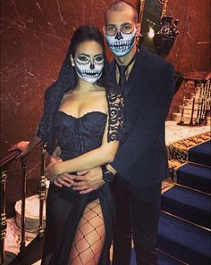 a man and woman dressed up in skeleton makeup pose for a photo on the stairs