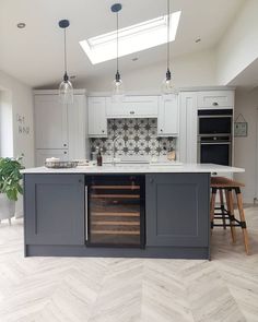 a kitchen with white cabinets and grey island