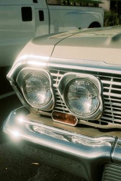 the front end of an old car parked in a parking lot next to other cars