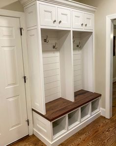 an empty white mudroom with wooden bench and storage cabinets on the wall next to it