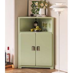 a green cabinet sitting in the corner of a room next to a lamp and pictures