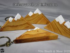 four wooden mountain shaped keychains on a white sheet with the words cedarwood of leeson written below them