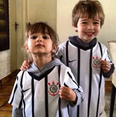 two young children standing next to each other wearing soccer uniforms and smiling at the camera