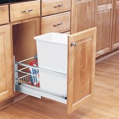 a kitchen with wooden cabinets and an open dishwasher drawer in the middle that is filled with food