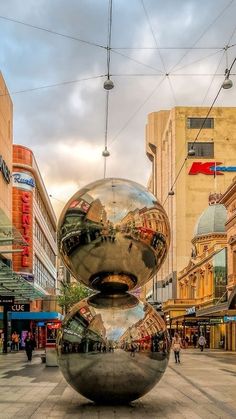 a large metal ball sitting in the middle of a street