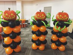 three pumpkins with black and orange balloons in the shape of vines on top of them