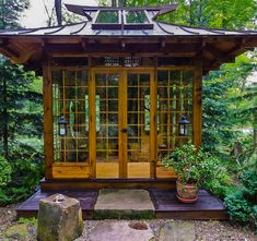 a small wooden structure with glass doors in the middle of some rocks and trees around it