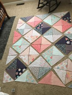 a child's rocking chair sitting on the floor next to a patchwork quilt