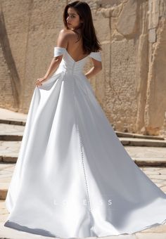 a woman in a white wedding dress standing on steps with her back to the camera