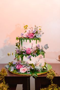 a three tiered cake decorated with flowers and greenery