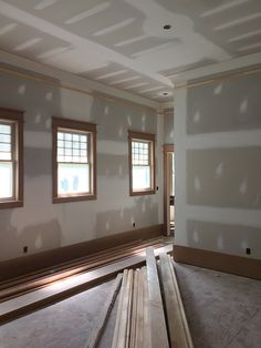 an empty room with three windows and some unfinished floor boards in the foreground,