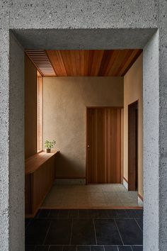 an empty room with tile flooring and wooden door leading to another room that has a plant in the corner