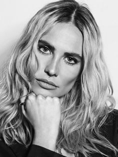 a woman with long blonde hair is posing for a black and white photo, her hand on her chin