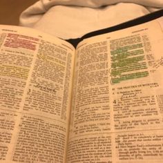 an open bible on a bed next to a white sheet with writing and numbers in it