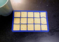 a blue and yellow ice tray next to a white cup