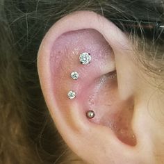 a close up of a person's ear with three diamond studs on it