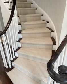 a set of stairs leading up to a second floor with white carpet and wood handrails