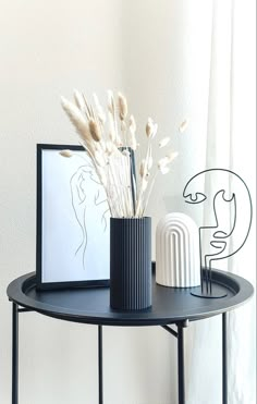 there are two vases with flowers on the table next to each other, one is black and white