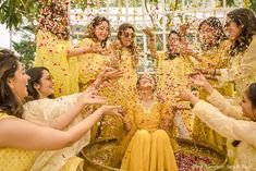 a group of women in yellow dresses throwing confetti into each other's eyes