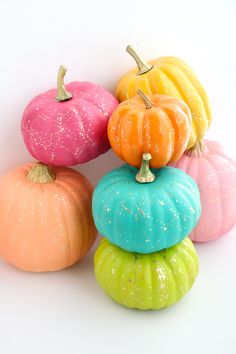 five small pumpkins are stacked on top of each other in different colors and sizes