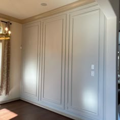 an empty room with white cabinets and wood floors