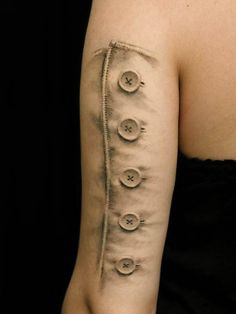 a woman with a tattoo on her arm that has buttons in the middle of it