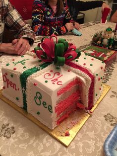 two people sitting at a table with a large cake in the shape of a gift