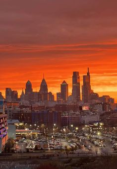 the city skyline is lit up at night with bright orange and pink clouds in the background