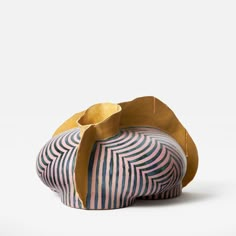 a striped vase sitting on top of a white table next to a brown paper bag