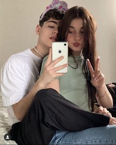 two people sitting on a bed taking a selfie