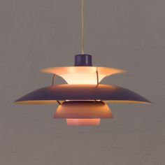 an unusual lamp hanging from a ceiling in the shape of a cone with two lights on each side