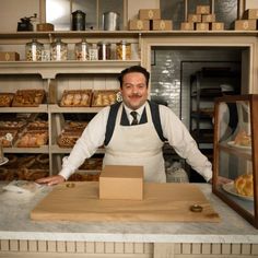 a man standing behind a counter in a bakery